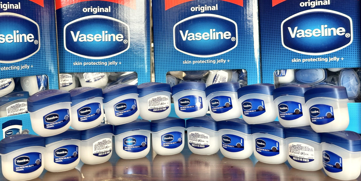Display of Vaseline products including jars and boxes on a reflective surface.
